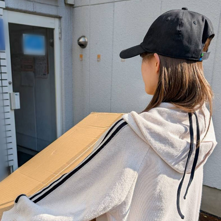 女性従業員が荷物の入った段ボール箱を運んでいる様子